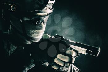 Army counter-terrorism squad, police SWAT team fighter hiding identity behind mask and glasses, wearing helmet with night vision-device, creeping in darkness, aiming service pistol during mission