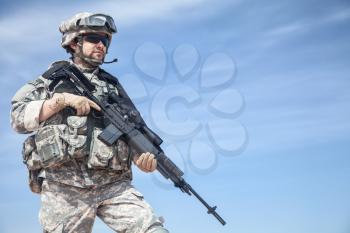 Portrait of United states airborne infantry marksman with arms, camo uniforms dress. Combat helmet on, tactical light, radio microphone, unshaven