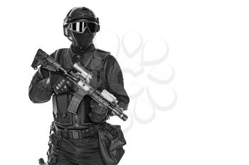 Studio shot of swat operator with assault rifle. Tactical helmet gloves, eyewear. Security forces concept