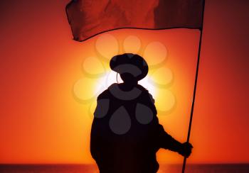 Silhouette of army soldier, commando fighter special forces infantryman standing on background of sunset sky waving on flagpole flag. Military victory, remembrance of fallen soldiers, veterans concept