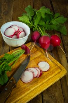 Bunch of fresh radish and salad on the old wood cutting board, vertical    
