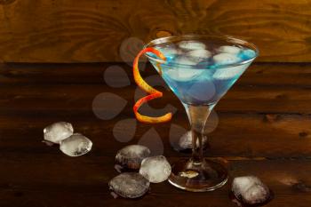 Blue Martini cocktail on the dark wooden background. Blue cocktail. Blue Martini. Blue Hawaiian cocktail. Blue curacao liqueur.  Blue margarita