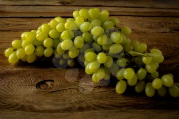 Bunch of green grapes on a dark wooden background. Fresh food. Ripe fruit. Citrus fruit. Vegetarian food. Mixed fruit. Fresh fruit.