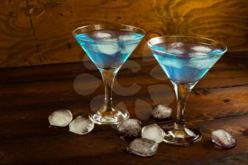 Two glasses of blue cocktail on dark wooden background. Blue Martini. Blue Hawaiian cocktail.
