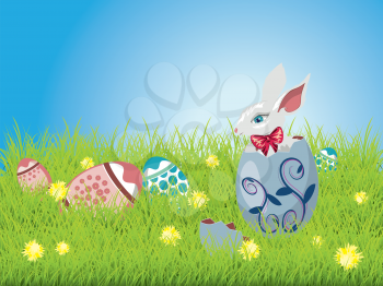Cute Easter bunny sitting inside a colorful cracked egg on grass field background.