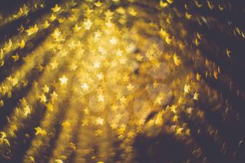 Festive background with defocused golden glitters, bokeh in a shape of a star.