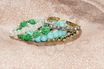 Stylish fashion bracelets with blue beads and pearls on glittering background.