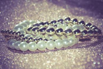 Stylish fashion bracelets with acrylic beads, pearls on vintage glittering background.