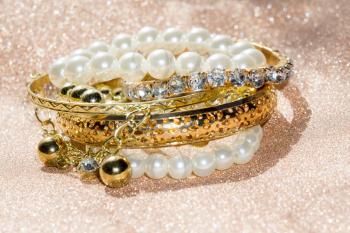 Stylish fashion bracelets with acrylic beads, pearls on glittering background.