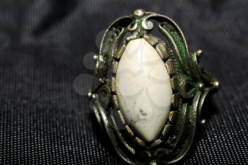 Vintage ring with decorative white stone on black textile macro.