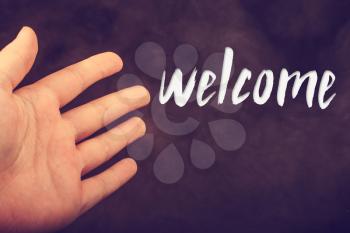 Hand making a welcome gesture on a dark background