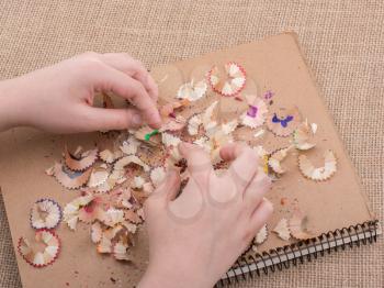 Colorful pencil shavings in hand on a notebook