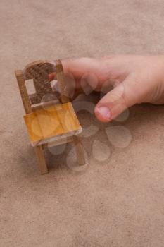 Child holding a  wooden  toy chair on brown background