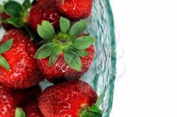 Glass bowl with fresh strawberries on white background. Selective focus macro.