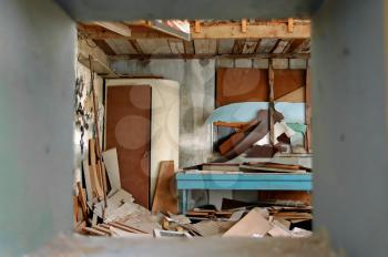 View to ramshackled room with boarded up window frame in abandoned factory.