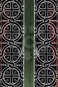Tangled circles and cross christian religious icon pattern detail on iron church door.