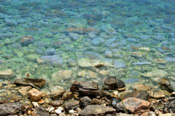 Clear blue sea water and stone beach background.