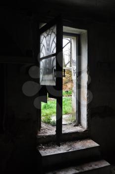 Dark abandoned house interior dirty steps and light through broken door with antique metalwork motif.