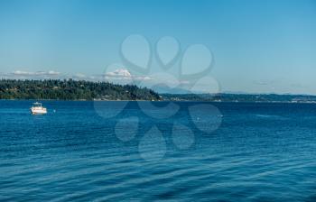 A boat is moored on the Puget Sound with Mount Rainier in the distance.