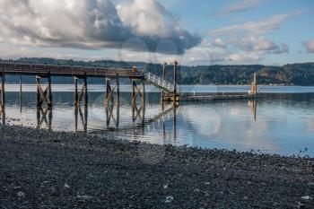 Veiw of the pier at Twahoh State Park in Washington State. The pier is on Hood Canal. Friendly clouds fill the sky.