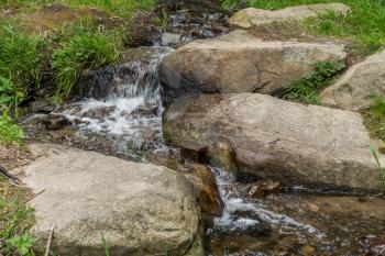 A stream rushes around boulders.