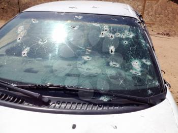 Automobile shot up bullet gun fire fight holes windshield broken glass