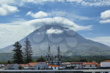 Pico mountain with clouds around its peak and port of Madalena, view from the sea, Azores, Portugal