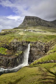 Gasadalur waterfall from viewpoint during a sunny autumn day with the water coming up under a strong wind (Faroe Islands, Denmark, Europe)