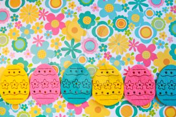 Decorated felt easter eggs yellow, pink and turquoise on a colorful flowers power style  background