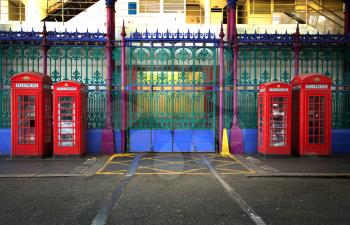 Four red booths in two different sizes with green, purple  and blue iron fence in background in Smithfield market in London UK