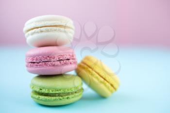 Pink, yellow, white and green traditional french macaroons on pink and blue background