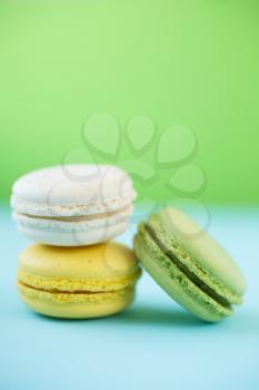 Pink, Yellow, white and green traditional french macaroons on green and blue background