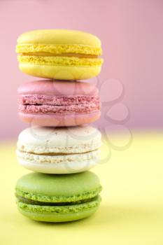 Pink, yellow, white and green traditional french macaroons on pink and yellow background