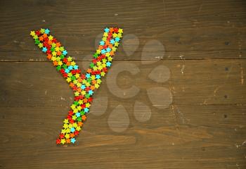 Letter Y from alphabet made with star shape candy on a wooden background
