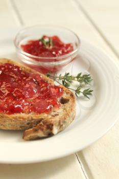 Wheat bread with homemade strawberry jam on a white plate on a white background