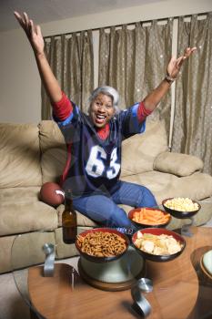 Royalty Free Photo of a Portrait of a Woman Wearing a Football Jersey With Hands in the Air Watching Football Game