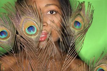 Royalty Free Photo of a Woman Looking Through Peacock Feathers