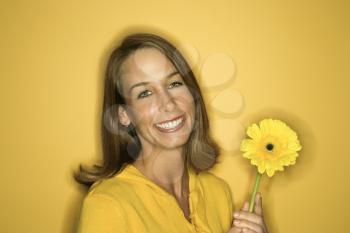 Royalty Free Photo of a Smiling Woman Holding a Flower