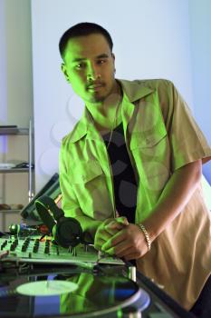 Royalty Free Photo of a Male DJ With Hand on Control Panels of Mixing Equipment