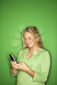 Royalty Free Photo of a Blond Teen Girl Smiling at a Cellphone