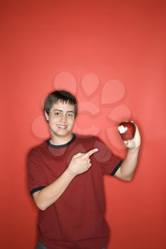 Royalty Free Photo of a Smiling Teen Boy Pointing to a Partially Eaten Apple