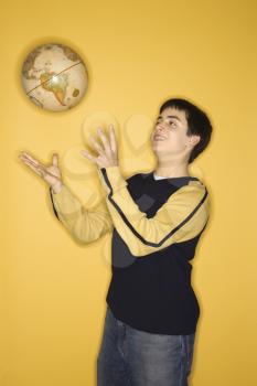 Royalty Free Photo of a Smiling Teen Boy Tossing a Globe in the Air