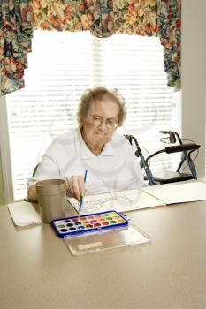 Royalty Free Photo of an Elderly Woman Painting With Watercolors at a Retirement Community Center