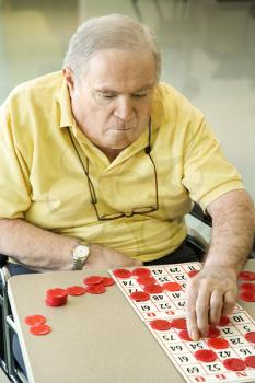 Royalty Free Photo of an Elderly Man Sitting in a Wheelchair Playing Bingo
