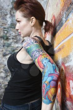 Royalty Free Photo of a Sexy Tattooed Woman Leaning on a Wall Covered in Graffiti
