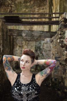 Royalty Free Photo of a Tattooed Woman Standing Next to a Concrete Wall