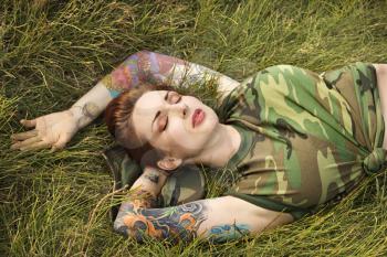 Royalty Free Photo of an Attractive Tattooed Woman in Camouflage Lying on Grass in Maui, Hawaii, USA