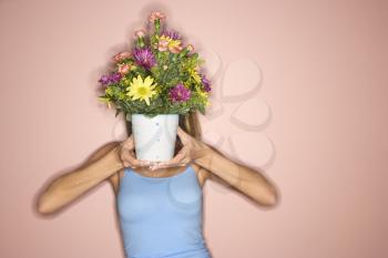 Royalty Free Photo of a Female Holding a Pot of Flowers in Front of Her Face