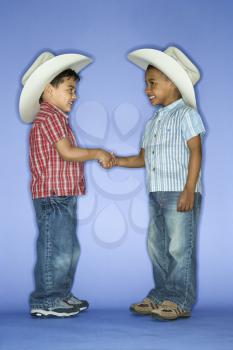 Royalty Free Photo of Boys in Cowboy Hats Shaking Hands