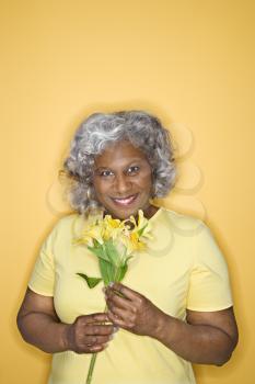 Royalty Free Photo of an Older Woman Holding Flowers and Smiling